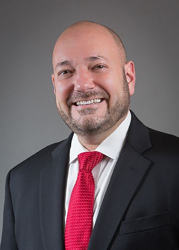 Alexander Hellinger, DPT, MBA, wearing a suit and red tie